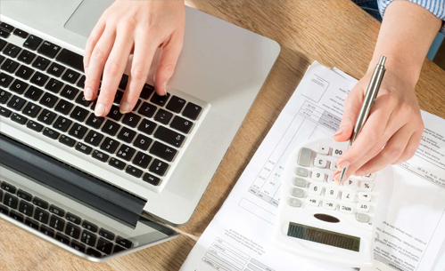 A picture of a person calculating and using laptop